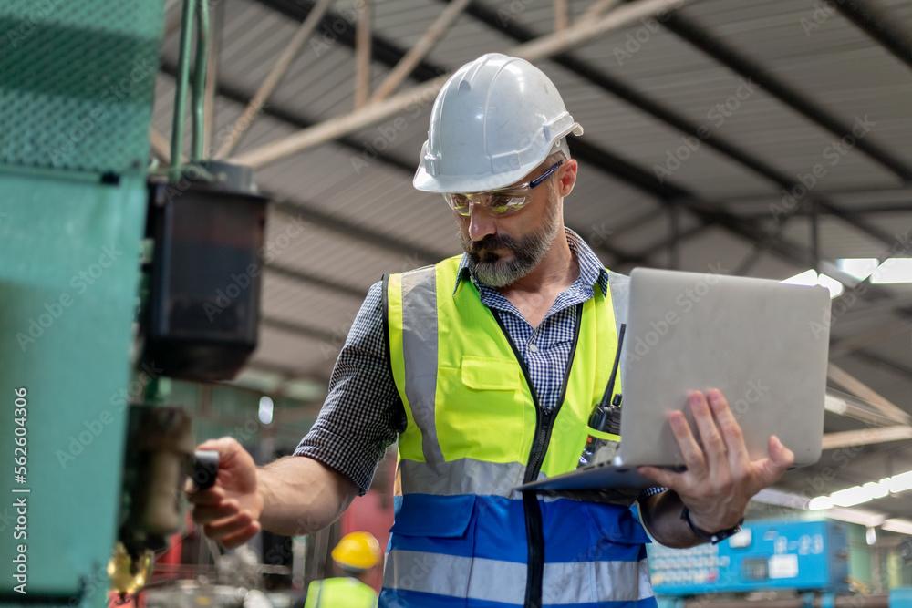 Field service engineer with a laptop checking equipment at a machine on site